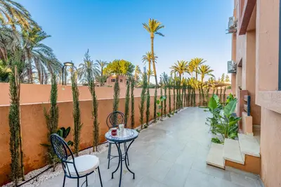 a patio with a table and chairs and palm trees at Grand duplex 4 ch - Piscine - Marrakech in Marrakech