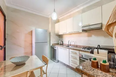 a kitchen with a table and a white refrigerator at Appartement spacieux 83 m carré Wi Fi Marrakech in Marrakech