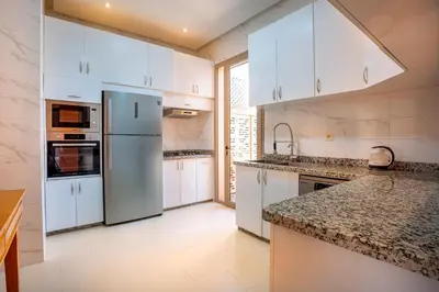 a kitchen with white cabinets and a refrigerator at Villa de luxe et plaisir in Marrakech