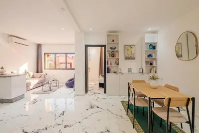 a kitchen and living room with a table and chairs at Modern & Cozy Apartment 2 min Carré Eden Guéliz in Marrakech