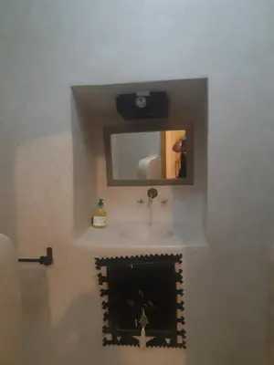 a bathroom with a sink and a mirror over a fireplace at Riad ICA in Marrakech