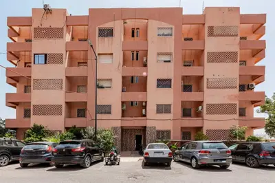 a large building with cars parked in a parking lot at 3 chambres lumineux au centre de Marrakech in Marrakech