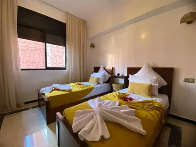 two beds in a room with yellow sheets at appartment L'Hivernage in Marrakech