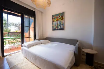 a bedroom with a white bed and a large window at 1 Bedroom Apartment with Private Garden, Terrace and Pool in Marrakech