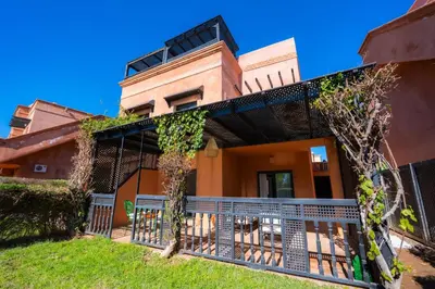 an orange house with a balcony with plants on it at 1 Bedroom Apartment with Private Garden, Terrace and Pool in Marrakech