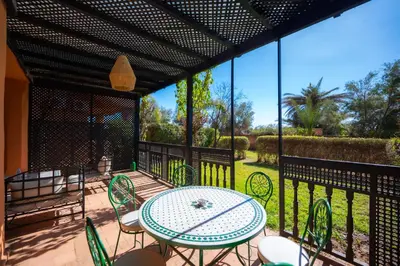 a patio with a table and chairs on a balcony at 1 Bedroom Apartment with Private Garden, Terrace and Pool in Marrakech