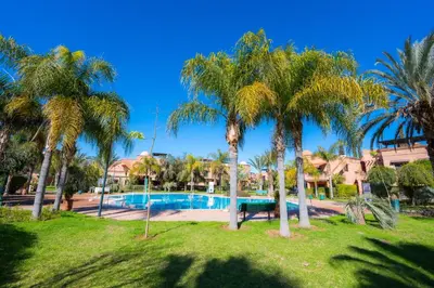 a resort with a swimming pool and palm trees at 1 Bedroom Apartment with Private Garden, Terrace and Pool in Marrakech