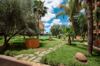 a park with palm trees and a swimming pool at Appartement idéal a l'hivernage in Marrakech