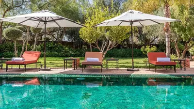 a group of chairs and umbrellas next to a pool at Villa Rehame in Oulad Jellal