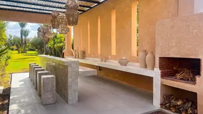 a patio with a fireplace and a table and chairs at Villa Olfa in Oulad Ikhia