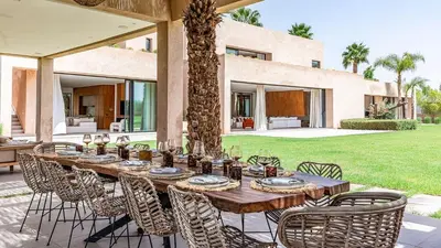 a long wooden table and chairs in front of a house at Villa Olfa in Oulad Ikhia