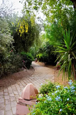 a brick path in a garden with flowers and trees at Nassim Al Noor in Marrakech