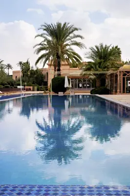 a large swimming pool with palm trees in the background at Nassim Al Noor in Marrakech