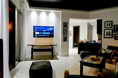 a living room with a table and a tv on the wall at Nassim Al Noor in Marrakech