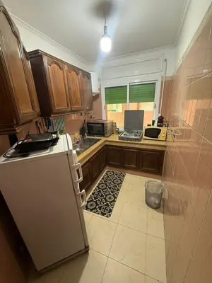 a kitchen with wooden cabinets and a white refrigerator at appartement Yasmine à Marrakech in Marrakech
