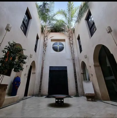 a building with palm trees and a table in a courtyard at RIAD Azur in Marrakech