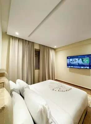 a bedroom with a large bed and a tv on the wall at Noraya Home - Secure residence with pool in Marrakech