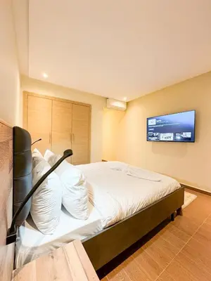 a bedroom with a bed with a tv on the wall at Noraya Home - Secure residence with pool in Marrakech