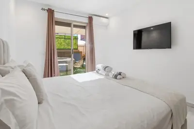 a bedroom with a white bed and a television at T2 - Terrasse et Jacuzzi - Coeur de Guéliz in Marrakech