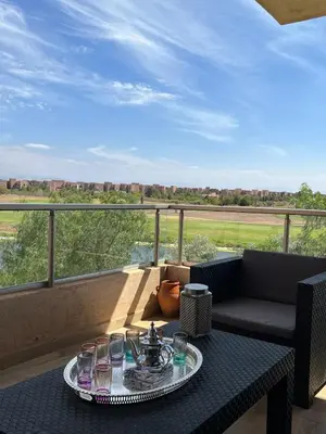a table with glasses on top of a balcony at Super 3-bedroom living room with view of Prestigia Golf Pools in Marrakech
