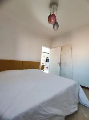 a bedroom with a white bed and a chandelier at Cocon calme et confortable wifi Netflix Gueliz Daoudiate in Marrakech