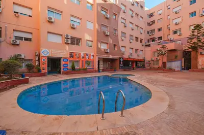 a swimming pool in a courtyard in front of buildings at Studio elegant raffine pour un sejour tout confort in Marrakech