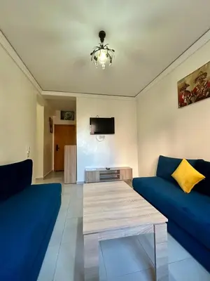 a living room with two blue couches and a tv at Appartement 2 chambres à 10mn du centre ville in Marrakech