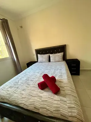a bed with two red pillows on it at Appartement 2 chambres à 10mn du centre ville in Marrakech