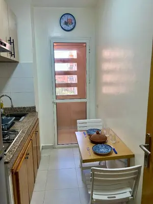 a kitchen with a table and chairs and a clock on the wall at Appartement 2 chambres à 10mn du centre ville in Marrakech