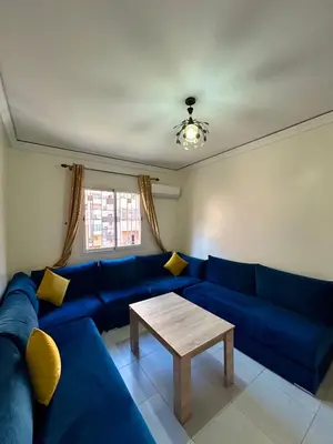 a living room with a blue couch and a table at Appartement 2 chambres à 10mn du centre ville in Marrakech