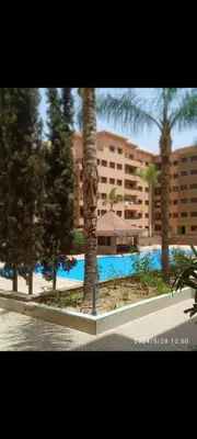 a resort with a pool and palm trees and a building at magnifique appartement Hivernage in Marrakech
