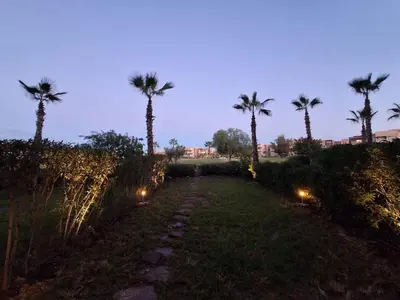 a path with palm trees and lights in a field at Prestigia Agathe in Marrakech