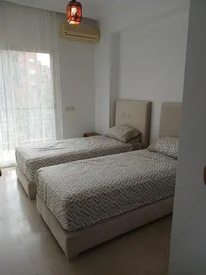 two beds sitting in a bedroom with a window at Appartement familial - 2 chambres - Hivernage in Marrakech