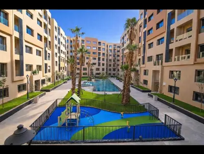 an apartment complex with a swimming pool and palm trees at Cozy & Modern Gueliz Apartment in Marrakech