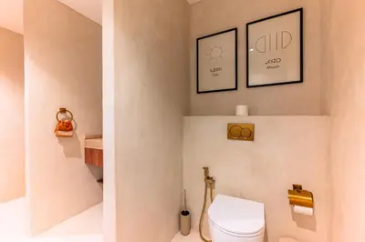 a bathroom with a toilet and two pictures on the wall at Suite Tifawt - Central, Design & Lumineux in Marrakech