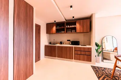 a kitchen with wooden cabinets and a mirror at Suite Tifawt - Central, Design & Lumineux in Marrakech