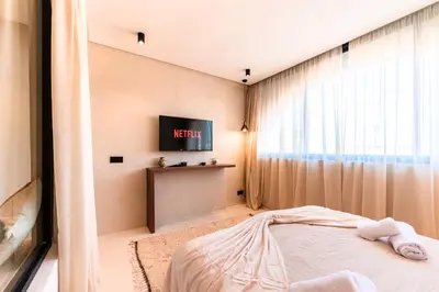 a bedroom with a bed and a tv on a wall at Suite Tifawt - Central, Design & Lumineux in Marrakech