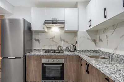 a kitchen with white cabinets and a stainless steel refrigerator at Moonlight Suite Pool and Relaxation in Marrakech