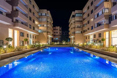 a swimming pool in front of buildings at night at Moonlight Suite Pool and Relaxation in Marrakech