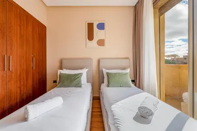 two beds in a room with a window at Prestigia Jubaea Apartment Green Escape & Pool in Marrakech