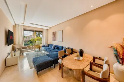 a living room with a blue couch and a table at Prestigia Jubaea Apartment Green Escape & Pool in Marrakech