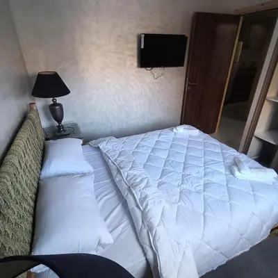 a bed with white sheets and a lamp and a television at Dolce appartement proche de l'aéroport in Marrakech