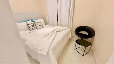 a small white bed with a black chair in a room at Luxury Family Apartment in Gueliz in Marrakech