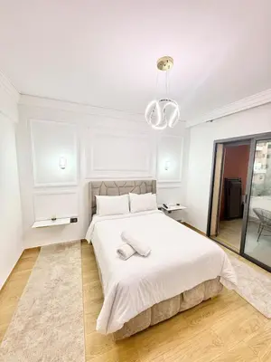 a white bedroom with a large bed and a chandelier at Elegant apartment with pool, highly desirable area in Marrakech