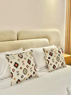 a bed with white sheets and pillows with a headboard at Modern apartment with jacuzzi & gym in Marrakech