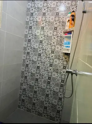 a shower with a black and white tile wall at Appartement near to big square in Marrakech