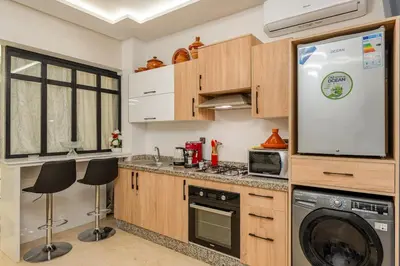 a kitchen with wooden cabinets and a washer and dryer at Beautiful apartment in residence with pool in Marrakech