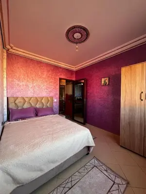 a bedroom with a large bed with purple walls at Apartment in Bassatine targa in Marrakech