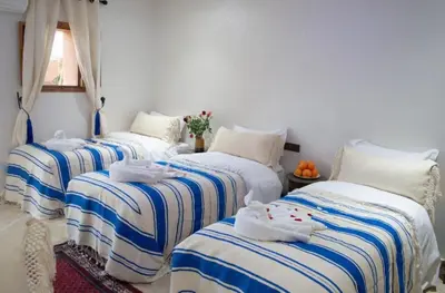 a room with three beds with towels on them at Villa Dar Saada in Marrakech