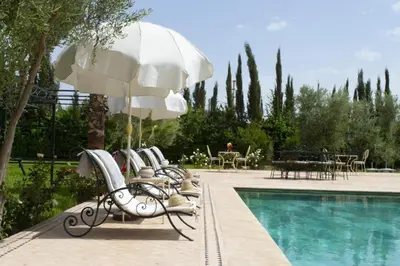 a swimming pool with chairs and an umbrella next to a pool at Villa Dar Saada in Marrakech